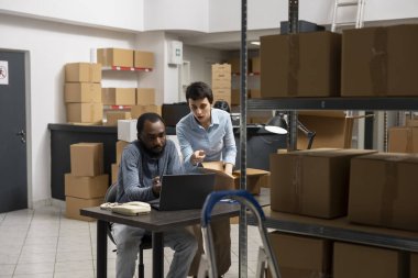 Çok ırklı çalışanlar, küçük bir depoda kasetlerle ve envanter raflarıyla çevrili yerel bir iş ekspres teslimatı üzerinde çalışıyorlar. Sanayi dağıtım lojistiği.