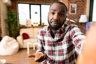 Uzaktan kumandalı erkek yönetici, iş arkadaşıyla video görüşmesi sırasında kameraya doğru hareket ederek şirket güncellemelerini tartışıyor. Afrikalı Amerikalı girişimci cep telefonuna sahip, müşterisiyle sanal toplantıya katılıyor.