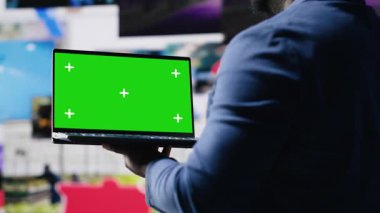 Dijital arayüzler ve multimedya görsellerinin yanındaki krom anahtar ekrana bakan Afrikalı Amerikalı teknoloji meraklısı, içerik oluşturma, mobil teknoloji ve küresel çevrimiçi etki sergiliyor. Kamera B.