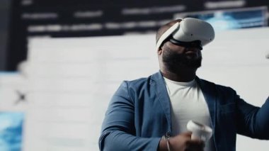 Afrika kökenli Amerikalı yazılım geliştiricisi sanal gerçeklik kulaklığını yüksek teknoloji arayüzü çalışma alanı olarak kullanıyor. Terminal pencerelerle çevrili, dijital programlama kültürünü temsil ediyor. Kamera B.