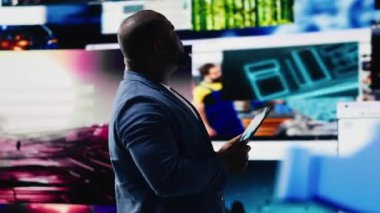 Afrikalı Amerikalı kullanıcı internet platformlarına ve uygulamalara bağlanarak çevrimiçi iletişim kavramını vurguluyor. Mobil teknoloji dijital uzayda sosyal ağ simgeleriyle çevrili. Kamera B.