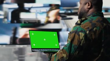 Kontrol kulesinde dizüstü bilgisayarı olan Afro-Amerikan askeri, başarılı bir ulusal savunma konusu için modern dijital aletler ve uydu görüntüleri kullanıyor. Kamera B.