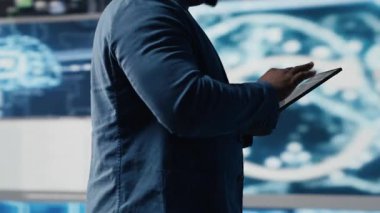 Fütürist dijital çalışma alanında, siyah geliştirici programlama yazılımı ve kod parçacıkları keşfediyor. Teknoloji profesyoneli yenilik, siber güvenlik, otomasyon ve geliştirmeyi somutlaştırır. Kamera B.