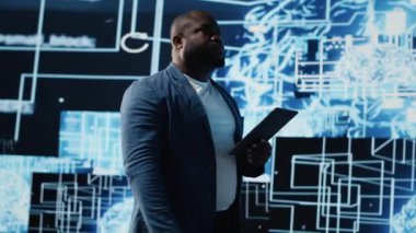 Yapay zeka veri görselleştirmesini ve nöral ağ platformlarını inceleyen genç siyah teknisyen, akıllı teknoloji siber uzay sistemleri. Makine öğrenme, bulut hesaplama ve Kamera B algoritmalarını inceler.