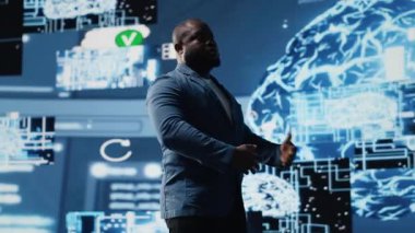 Teknolojiden anlayan siyah erkek mühendis, sanal yardımcı geliştirme ve bilişim otomasyon sistemleri için gelişmiş programlama ve bulut hesaplama araçları kullanarak büyük veri yapay zekası beynini inceliyor. Kamera B.