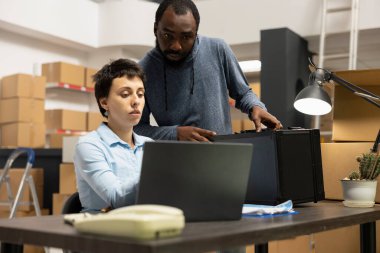 Küçük işletme tatbikat merkezinde çeşitli çalışanlar yerel nakliye ve envanter işlemlerini yönetiyor. Kasetlerle ve depolama birimleriyle dolu bir depoda birlikte çalışıyorlar..