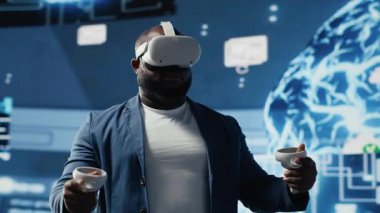 Siyah işadamı, dijital veri işleme ortamında veri bilimi, otomasyon ve yapay zeka etiğini keşfetmek için ileri teknoloji VR kulaklık araçları kullanıyor. Makine öğrenme üzerinde çalışıyor. Kamera B.