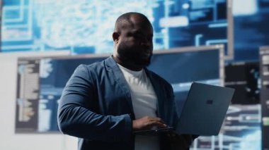 Siyah kodlayıcı yüksek teknolojili çalışma alanında dizüstü bilgisayarla programlamaya odaklanmış, otomasyon için terminal penceresine ikili kod yazıyor. Veri biliminde profesyonel teknoloji kariyeri. Kamera B.