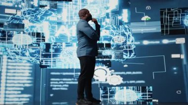 Siyah erkek uzman yapay zeka araştırmalarında veri yapıları veya platformlar ve akıllı teknoloji sistemleri ile etkileşim içinde. Derinlemesine öğrenim, bulut hesaplama ve öngörücü analitik çalışmaları yapıyor. Kamera A.