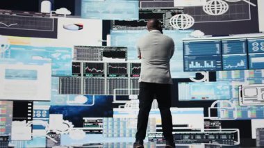 Afrikalı Amerikalı bir adam, yeni gelişmeler için yıllık mali raporları yansıtıyor, performans analizinin karmaşıklığını verimlilik ve öngörü üzerine odaklanarak gözden geçiriyor, yapay zeka araçları. Kamera A.