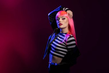 Vahşi kadın, parlak stüdyo ışıkları altında keskin bakışlar ve anlamlı makyajlar sergiliyor. Moda kıyafetleri içinde poz veren genç bir kadın model fotoğraf çekimi sırasında güven içinde duruyor..