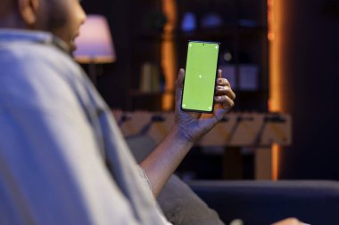 Afrikalı Amerikalı uzaktan kumandalı işçi oturma odasında çalışmak için krom anahtar ekranı kullanıyor, modern şık oturma odasındaki kanepede oturuyor. İnternetteki genç mutlu yetişkin.