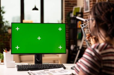 Freelancer evde çalışır, yeşil ekranlı bilgisayar kullanır, düzenleme veya sunum için şablonu inceler. Kadın uzaktan kumandalı çalışan, elinde bir panoyla, izole edilmiş krom anahtar görüntüsüne bakıyor..