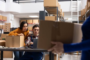 İşçi takımı siparişleri ve perakende sevkiyatları bantlı kutular ve etiketli paketlerle küçük bir depoda işliyor. Verimli lojistik ve dağıtım hizmetleri tarafından desteklenen yerel marka tatmini.
