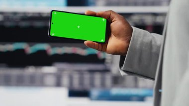 Afrika kökenli Amerikalı iş adamı KPI metriklerinin yanındaki yeşil ekranı kullanarak, şirketin yüksek kalitede bir yaşam sürmesini sağlıyor. Genç girişimci, fintech projeksiyonlarını inceliyor. Kamera B.