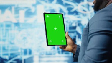 Afrika kökenli Amerikalı uzman, bulut hesaplama sistemlerinin yanında izole bir ekranla yapay zeka beyin gelişimine ve inovasyon için makine öğrenmesine odaklanmış bir tablet tutuyor. Akıllı teknoloji veri bilimi. Kamera B.