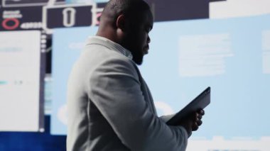 Afrikalı Amerikalı iş adamı, fon elde etmek için yeni güçlü fikirler, finansal ve KPI projeksiyonları için veri içgörüleri ve karar verme mekanizması üzerinde kafa yoruyor. Verimlilik için tahmin yürütüyorum. Kamera B.