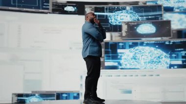 Otomasyon için programlama dilini analiz eden Afro-Amerikan mühendis, arkasında geleceksel bir arayüzü olan veri bilimi. Erkek teknisyen yapay zeka ve kod parçacıklarıyla başarılı oluyor. Kamera A.