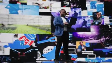 Siyah sosyal medya yöneticisi uygulama arayüzleri, bilgi grafikleri ve sosyal ağ beslemeleri ile yüksek teknoloji ortamını tarıyor. Sosyal medya platformları ve multimedya hakkında büyük veriler. Kamera A.