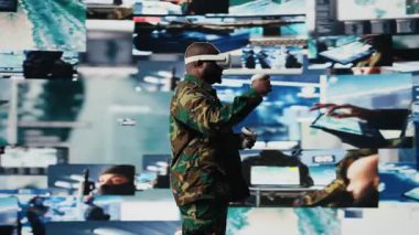 Afrika kökenli Amerikalı asker güvenlik kamerası görüntülerini izlemek için sanal gerçeklik kulaklığı kullanıyor. Etkileşimli bir cihaz kullanarak ulusal savunma görevinin başarıya ulaşmasını sağlıyor. Savaş bölgesi operasyonları. Kamera A.