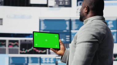 Siyah iş adamının elinde yeşil ekranlı ve kontrol paneli olan bir cihaz var. Ekonomi endüstrisinde başarı elde etmek için iş verimliliği sağlıyor. Performans ölçümleri ve içgörü. Kamera B.