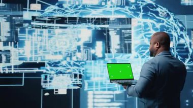 Siyah yüksek teknoloji mühendisi, sanal zeka ve platform yenilikleri için öngörücü analitik ve sinir ağları sistemlerini inceleyen izole edilmiş ekranlı telefonu tutuyor. Kamera A.