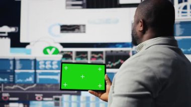 Siyah iş adamının elinde yeşil ekranlı ve kontrol paneli olan bir cihaz var. Ekonomi endüstrisinde başarı elde etmek için iş verimliliği sağlıyor. Performans ölçümleri ve içgörü. Kamera A.