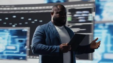 Programlama ve otomasyon üzerine çalışan Afro-Amerikalı geliştirici arkasında gelecekteki arayüzü olan bir dizüstü bilgisayarda kodlama yapıyor. Teknoloji profesyoneli yapay zeka ve kod parçalarından oluşan bir dünyada gelişiyor. Kamera B.