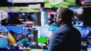 Afrika kökenli Amerikalı kullanıcı, izole edilmiş bir model ekran, dijital ağ sistemi ve gösterge paneli üzerinde uygulamaları olan bir telefon tutuyor. Yapay zeka ve Fintech 'in entegrasyonu vurgulanıyor. Çoklu görev. Kamera A.