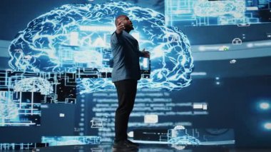 Teknolojiden anlayan siyah erkek mühendis, sanal yardımcı geliştirme ve bilişim otomasyon sistemleri için gelişmiş programlama ve bulut hesaplama araçları kullanarak büyük veri yapay zekası beynini inceliyor. Kamera A.