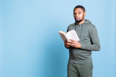 Kendine güveni tam, mavi arka planda kitap okuyan, kendini mutlu hisseden ve hobisinden zevk alan biri. Genç yetişkin kitap kurdu edebiyat hakkında eğleniyor, stüdyoda kitap sever..