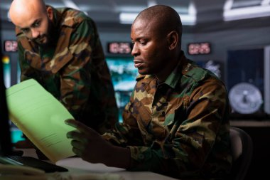 Ordu subayı görev faaliyetlerini organize etmek için istihbarat belgeleri okuyor. İstihbarat uzmanı düşman birliklerinin gelişimini ve tehditlerini değerlendirmek için istihbarat bilgilerini analiz ediyor.