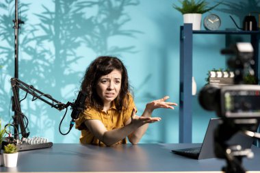 Kadın canlı yayında izleyicilere son zamanlardaki haber başlıklarını anlatıyor, hikayeyle ilgili üzgün hissediyor, dizüstü bilgisayardan okuyor. Çevrimiçi program sunucusu dizüstü bilgisayardan okunan bilgilerden şikayetçi