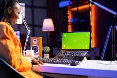 Oturma odasındaki tele-işçi iş ortaklarından gelen e-postaları cevaplamak için krom anahtar dizüstü bilgisayar kullanıyor. İzole ekran aygıtı klavyesinde yazan, dairedeki görevleri çözen uzak çalışan