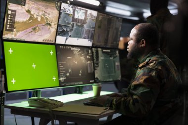 Askeri erken uyarı sistemi operatörü yeşil ekran uydu teçhizatı kullanarak düşman hava saldırılarını izliyor. Karargâhtaki asker kroma radarıyla hava sahası üstünlüğünü koruyor.