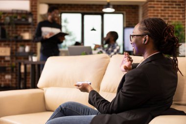 Siyahi kadın girişimci, holografik arayüzle iletişim kurmak ve ileri teknoloji çalışma alanında veri sunmak için fütüristik aygıt kullanıyor. Arkadaki Afrikalı Amerikan takımı başlangıç sinerjisini sembolize ediyor.