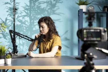 İçerik üreticisi profesyonel mikrofonu daha yakına yerleştiriyor, yaklaşan video için temiz ses yakaladığından emin oluyor. Vlog kaydedicisi ses seviyelerini kontrol eder, sesi dengelemek için hafif ayarlamalar yapar