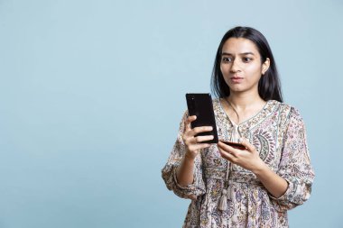 Cep telefonuna bankacılık bilgilerini ekleyen iyimser biri ödemeyi ve para transferini bir web sitesinden onaylıyor. Genç Hintli yetişkin internetten satın alıyor. Stüdyo arka planında kart kullanıyor..