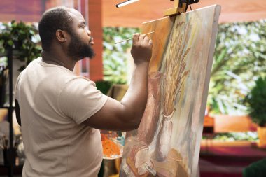 Afrika kökenli Amerikalı sanatçı, sanat stüdyosunda yeni bir eser yaratmak için yeteneğini kullanıyor ve başyapıtı için yenilikçi resim tekniğini kullanıyor. Genç çağdaş ressam bir sanat eseri üzerinde çalışıyor..