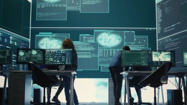 Hükümet hackerları bilgisayar sistemlerini siber tehditlerden koruyorlar. Teşkilat kontrol odasında birlikte çalışıyorlar. Şifreleme, çevrimiçi güvenlik ve siber saldırılara karşı casusluk. Kamera B.