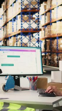 Vertical Video Depot Asyalı işçi bilgisayardaki online alışveriş siparişlerini işliyor, sevkiyat detaylarını yönetiyor ve profesyonel yazılımın gizli numaralarını kontrol ediyor. Paketleme ve envanter işlerini hallediyor. Kamera A.