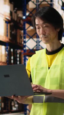 Dikey video çoklu etnik personel e-ticaret siparişlerini işliyor ve faturaları gözden geçiriyor, depolama raflarıyla endüstriyel depo alanındaki kargo mallarını düzenliyor. Düzgün dağıtım ve kalite kontrolü