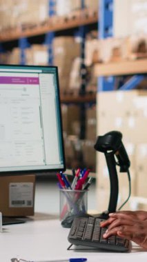 Bir dağıtım merkezinde ambalaj işlemleri sonrasında barkod sevkiyat etiketlerini kaydetmek için tarayıcı kullanan dikey Video Black çalışanı, sonraki sipariş takibi için awb etiketlerini tarıyor. Depo odası. Kamera.