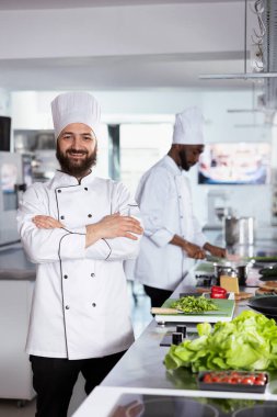 Mutfakta gastronomi uzmanı taze malzemelerle yemek hazırlıyor, modern mutfak aletleri ve meslektaşlarıyla tezgahlarda çalışıyor. Gurme meslek ve kariyer.