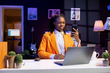 Oturma odasında genç bir kadın akıllı telefondan mesaj yazıyor. Gen Z kişisi cep telefonu tutuyor, arkadaşlarıyla çevrimiçi mesajlaşma uygulaması üzerinden sohbet etmekten keyif alıyor.