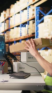 Dikey video Asyalı erkek işçi barkodları taramak için yapay zeka beynini kullanıyor, rota detayları için rota bilgileri ve yapay zeka destek araçları kaydediyor. Depoda sanal yardım. Kamera.