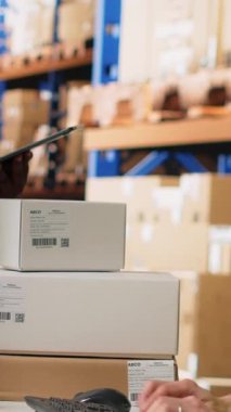 Depo arz ve talep işlemlerini tamamlayan dikey video ekibi bilgisayar monitöründen sevkiyat detaylarını kontrol ediyor. E-ticaret deposu. Kamera B.