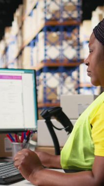 Dikey Video Genç kadın, depo operasyonlarını yürütmek için yapay zeka otomasyon sistemleriyle barkodları tarıyor, takip yazılımlarını yönetiyor. Yoğun dağıtım merkezindeki etiketlerin sevkiyat detayları. Kamera.