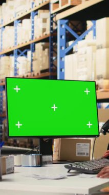 Dikey Video Siyah kadın çalışanı yeşil ekran, depo otomasyon araçları ve envanter kontrol panellerinin yanında siparişleri yönetir. Depolama rafları ile e-ticaret siparişi işlem