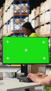 Dikey Video Asyalı personel paket izleme yazılımında izole edilmiş ekran nakliye rotasına bakıyor, havayolu faturalarındaki teslimat detaylarını güncelliyor. Depoda çalışıyor, bilgisayarında yeşil ekran var.